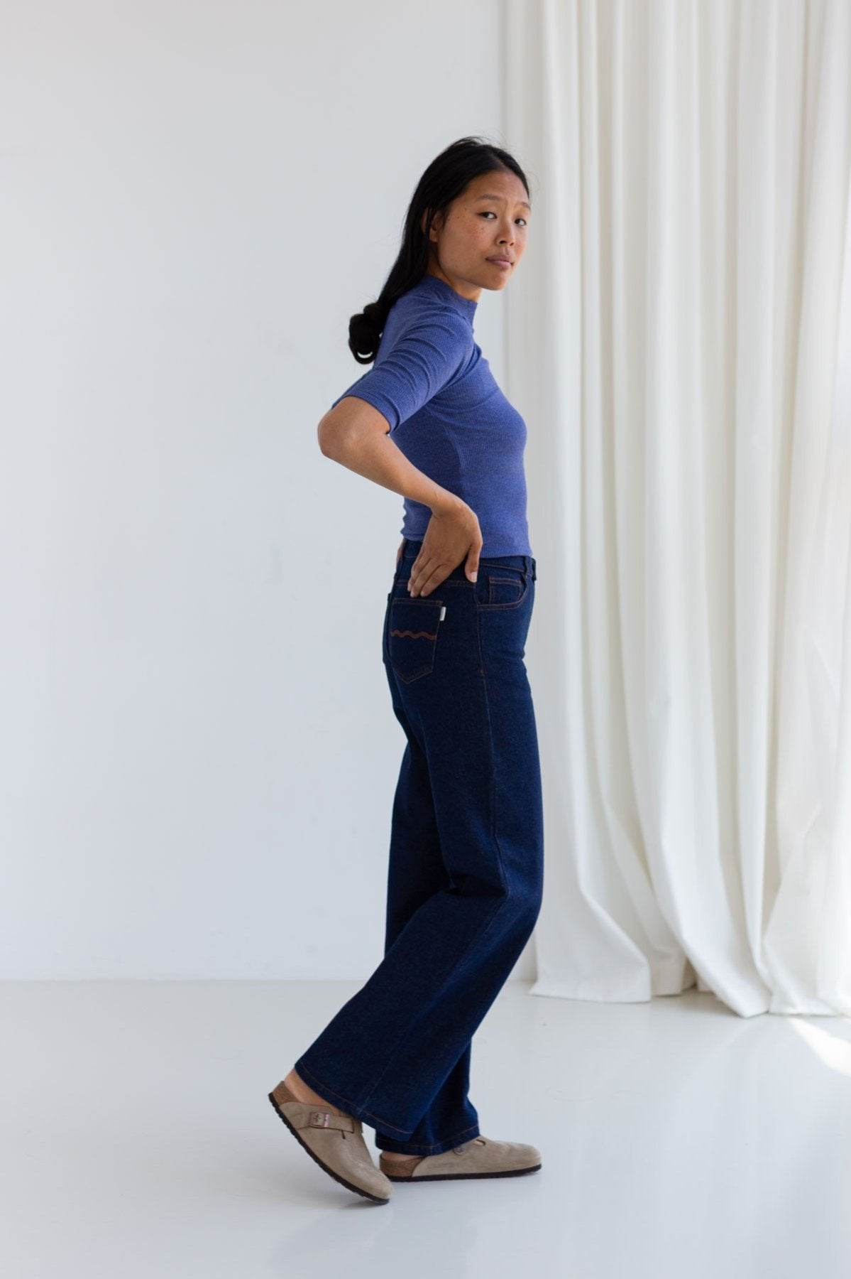 Woman in a mazarine blue ribbed top and dark wide-leg jeans.