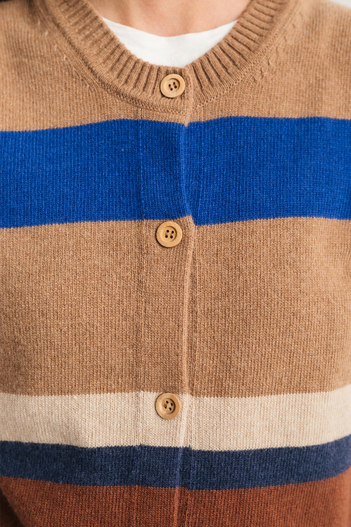 close-up of eco-conscious striped vest with natural wood buttons