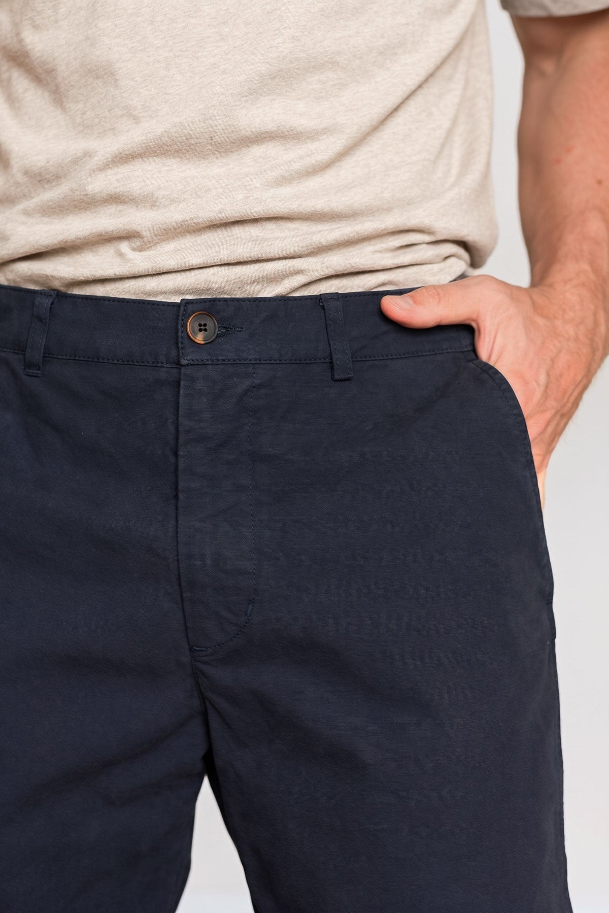 Close-up front view of the waistband, button closure, and side pocket on midnight blue pants.