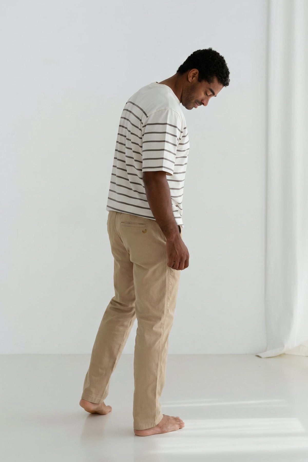 Back view of man wearing a striped shirt and beige pants.