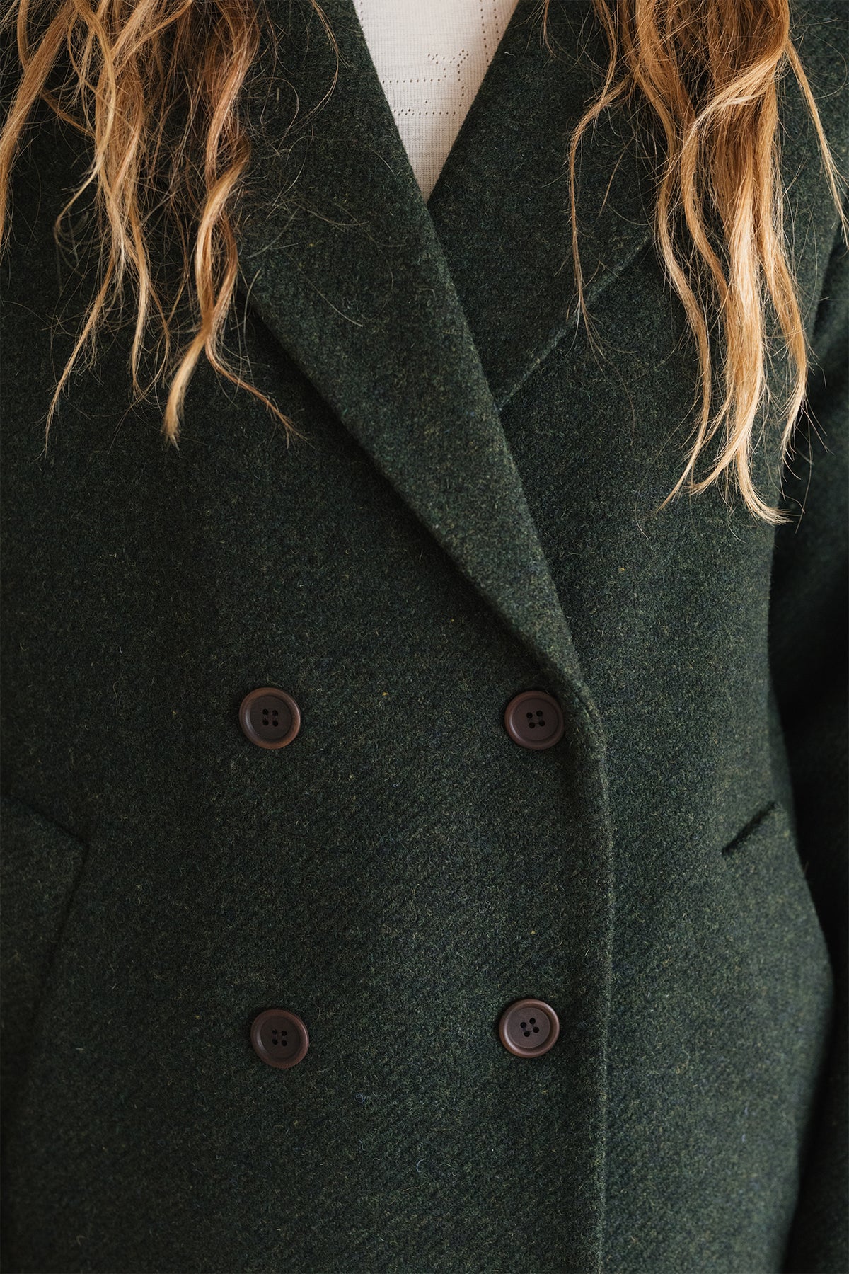 Close-up of a dark green wool coat with brown buttons
